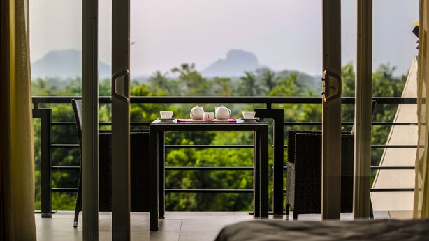 A balcony with a table set for tea, overlooking lush greenery and distant mountains. - Cassandra Culture Resort (Avudangawa)
