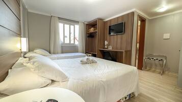 Camera d'albergo con due letti, una televisione, una scrivania con una sedia e un piccolo tavolino con un telecomando.