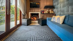 A modern living room with a fireplace, a blue sofa, and a television mounted on the wall. - Pousada Viena (Gramado)