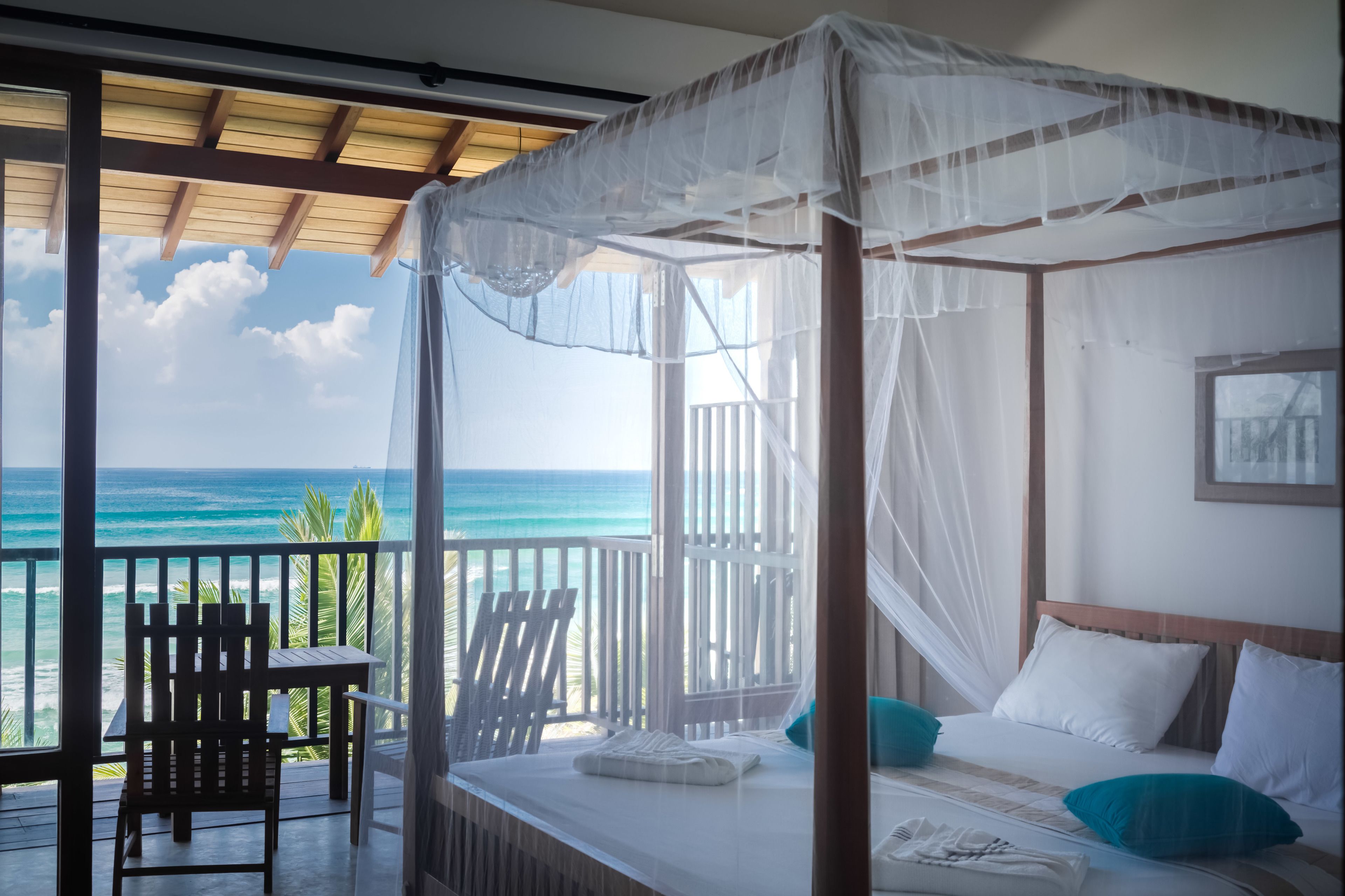 A room with a bed, a chair, and a view of the ocean.