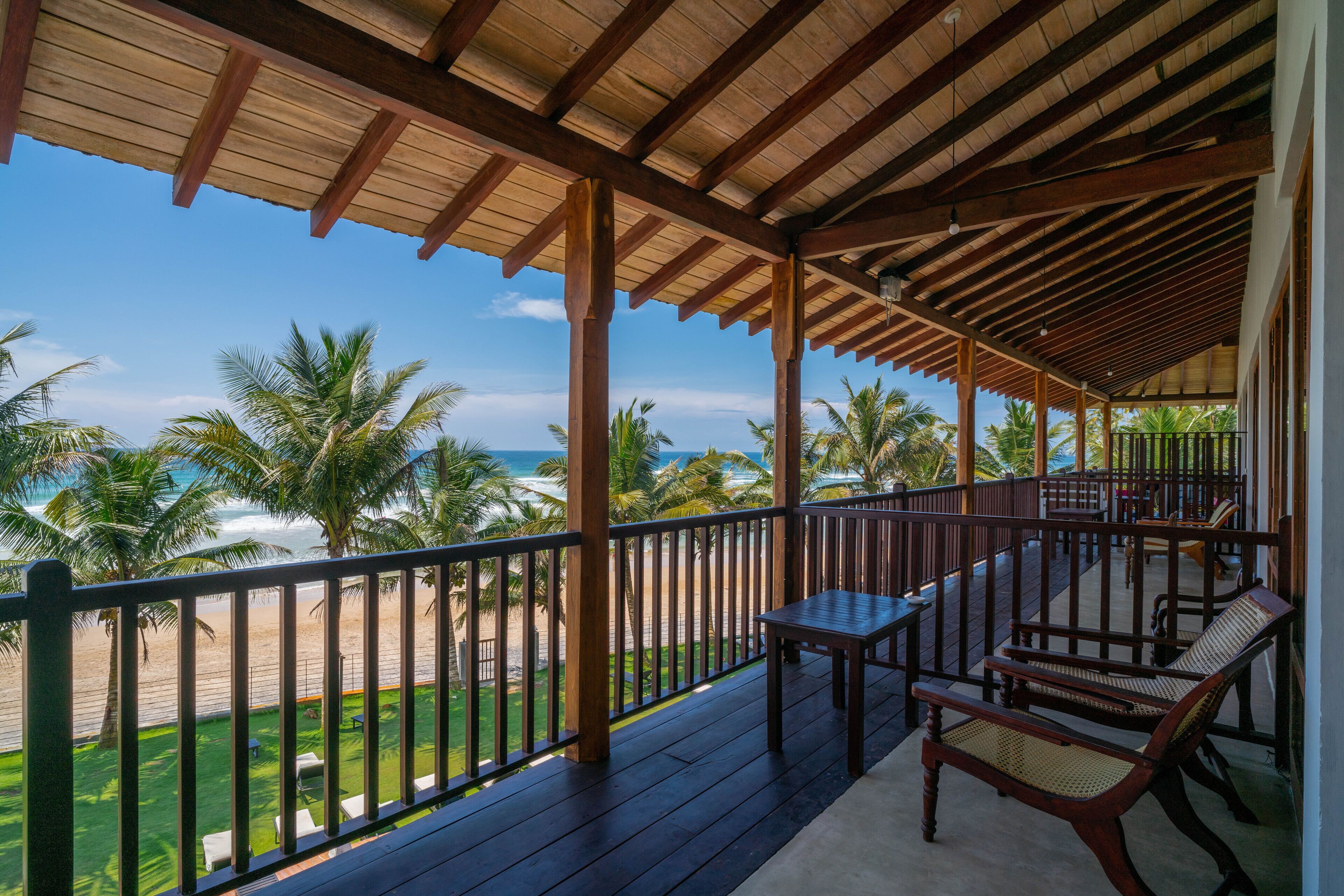 A wooden deck with a view of the beach and palm trees.