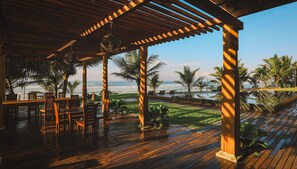 A wooden deck with a view of the ocean, outdoor seating, and palm trees. - Timeless Villa (Ahangama)