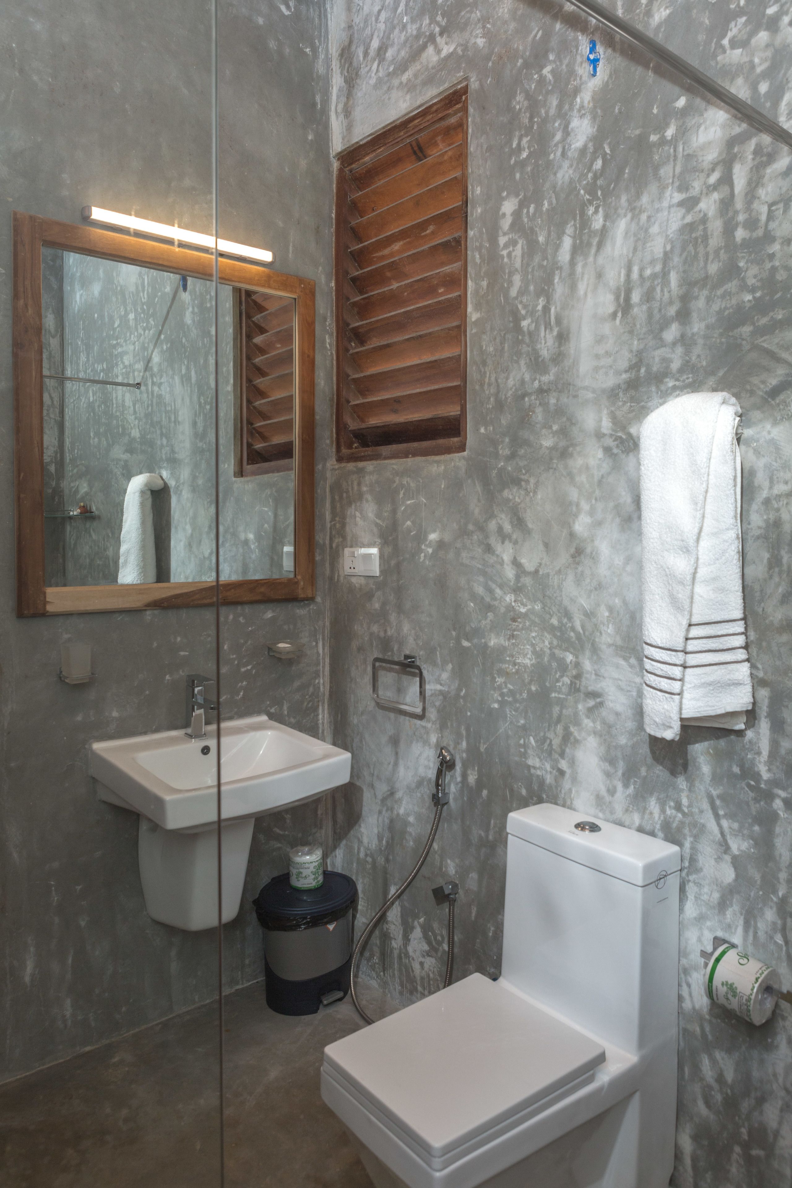 A bathroom with a white sink, mirror, toilet, and towel hanging on the wall.