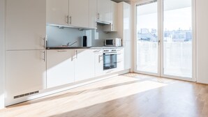 A modern kitchen with white cabinets, a microwave, and an oven.