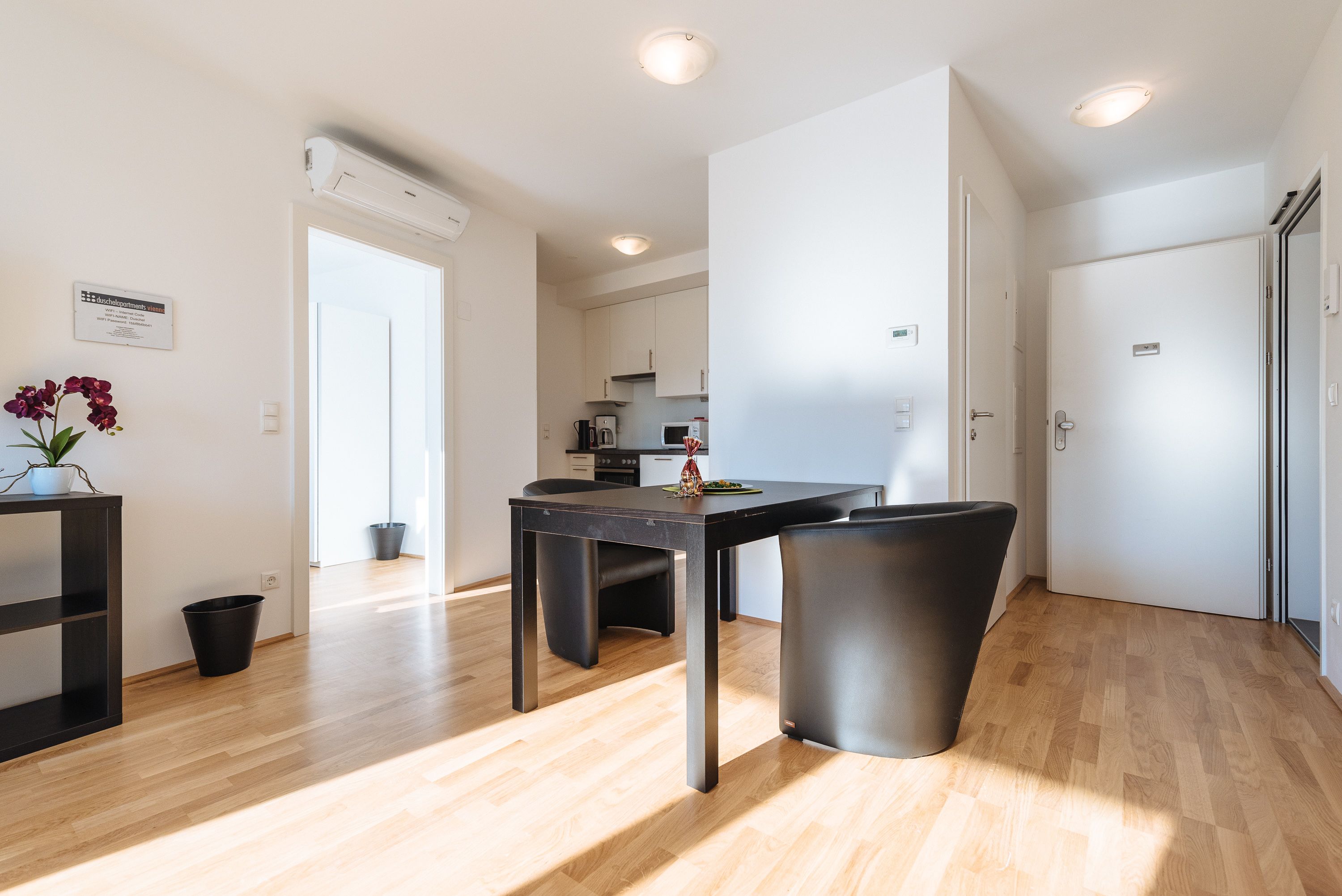 Una cocina moderna con armarios blancos, una encimera negra y un comedor con una silla y una mesa negros.