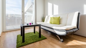 A modern living room with a white sofa, a green rug, and a black coffee table.