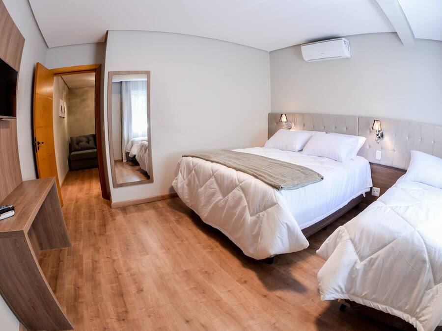 Una habitación de hotel con una cama, mesitas de noche, un televisor y un espejo.