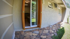 A house with a stone foundation, a sliding glass door, and an air conditioning unit. - Viena Flats (Gramado)