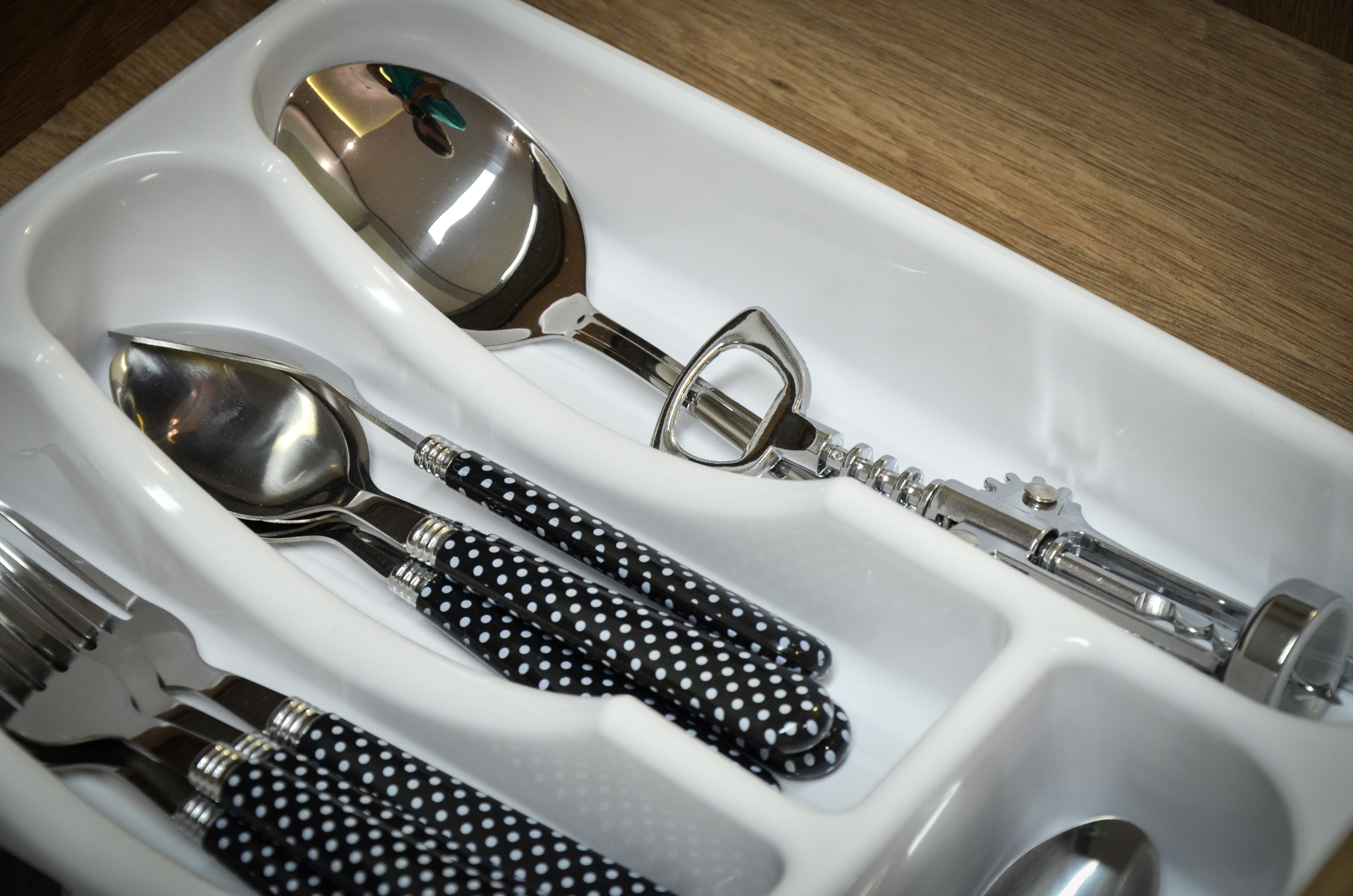 A white tray with utensils including a spoon, fork, and bottle opener.