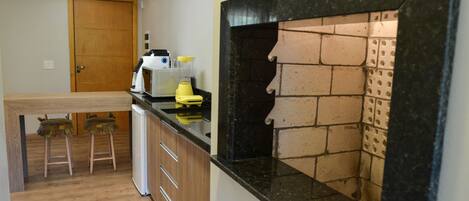 A kitchen with a wooden door, a countertop with a blender, and a brick-patterned backsplash.
