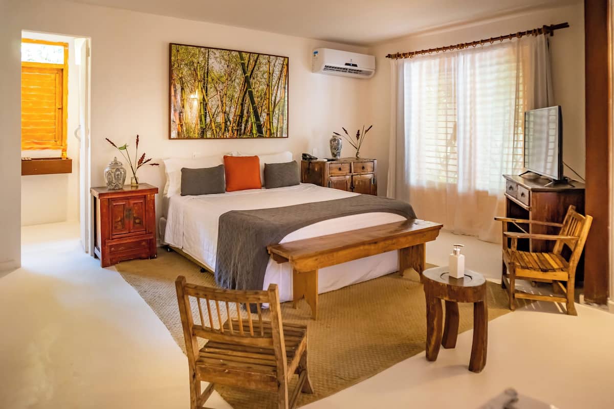 Una camera da letto con un letto, mobili in legno, un quadro e un condizionatore.