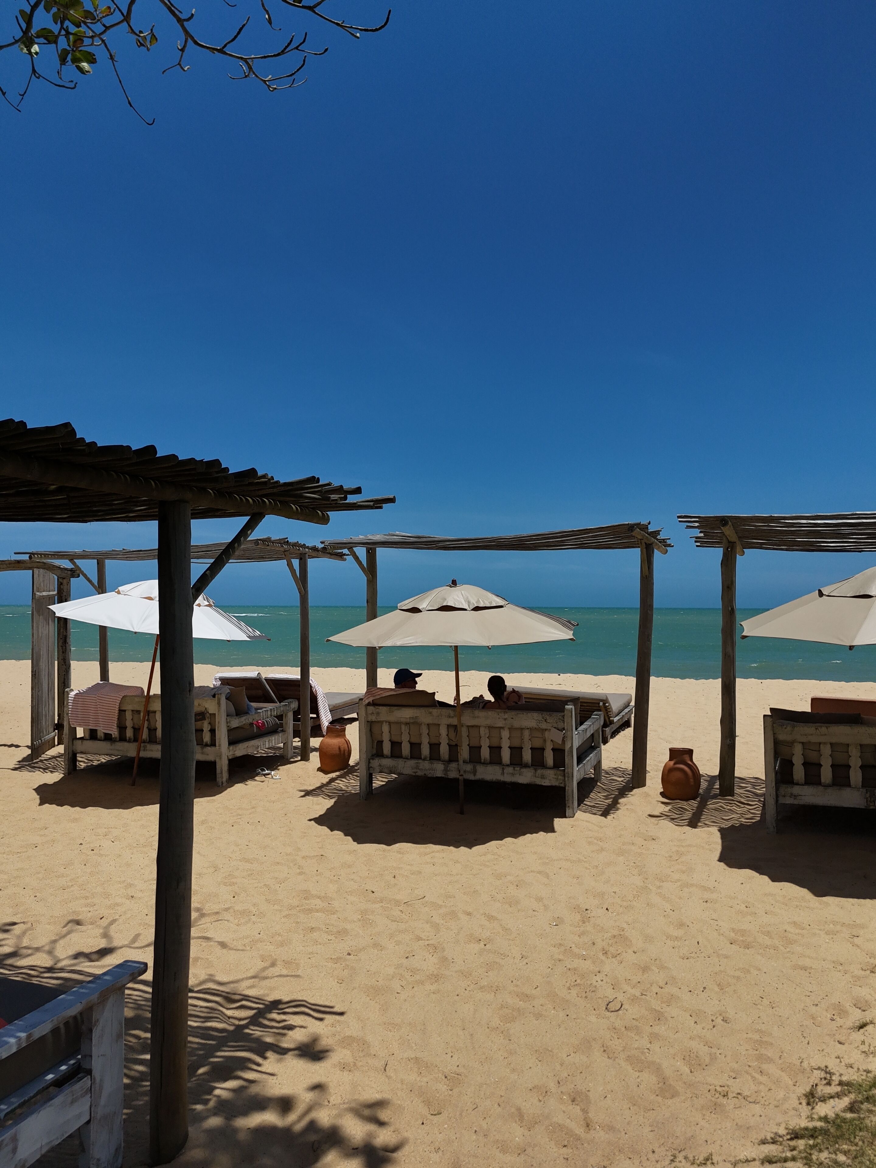 A beach with wooden benches and umbrellas, providing shade and seating.