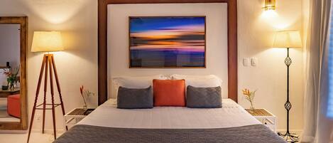 Una camera d'albergo con un letto grande, un quadro appeso al muro e due lampade da comodino.