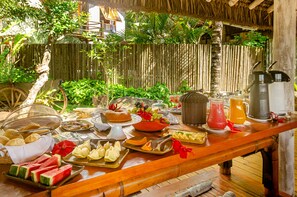 A breakfast buffet with various food items and drinks on a wooden table. - Villas de Gaia Hotel Boutique (Porto Seguro)