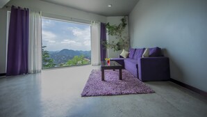 Una sala de estar moderna con un ventanal grande, un sofá morado, una mesa de centro y un ventilador de techo.