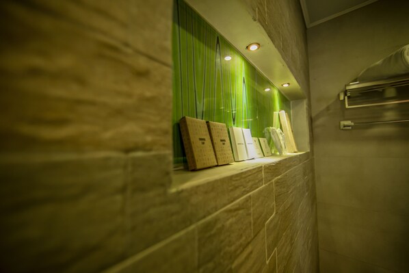 A bathroom with a marble wall, a green vertical panel, and a towel rack.