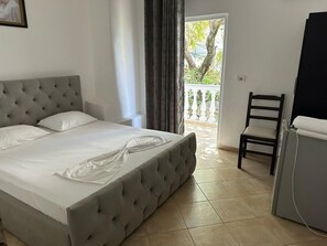 A bedroom with a tufted headboard bed, a chair, and a desk. - Hotel Rixhi (Sarandë)