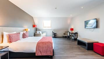 A modern hotel room with a large bed, a desk, a chair, a TV, and a small table.