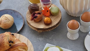 A breakfast table with croissants, pastries, cheese, grapes, strawberries, and a glass of orange juice.