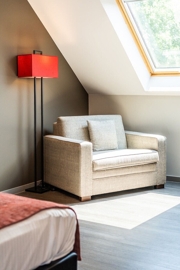 A modern room with a sofa, a red floor lamp, and a skylight. - Hôtel Golf Relais de l'Empereur (Genappe)