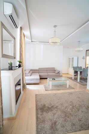 Una sala moderna con un sofá seccional, una mesa de centro de vidrio y una chimenea.