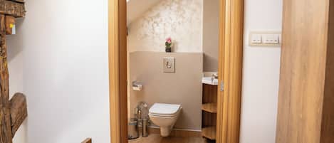 A wooden-framed doorway leading to a bathroom with a toilet, sink, and shelves.