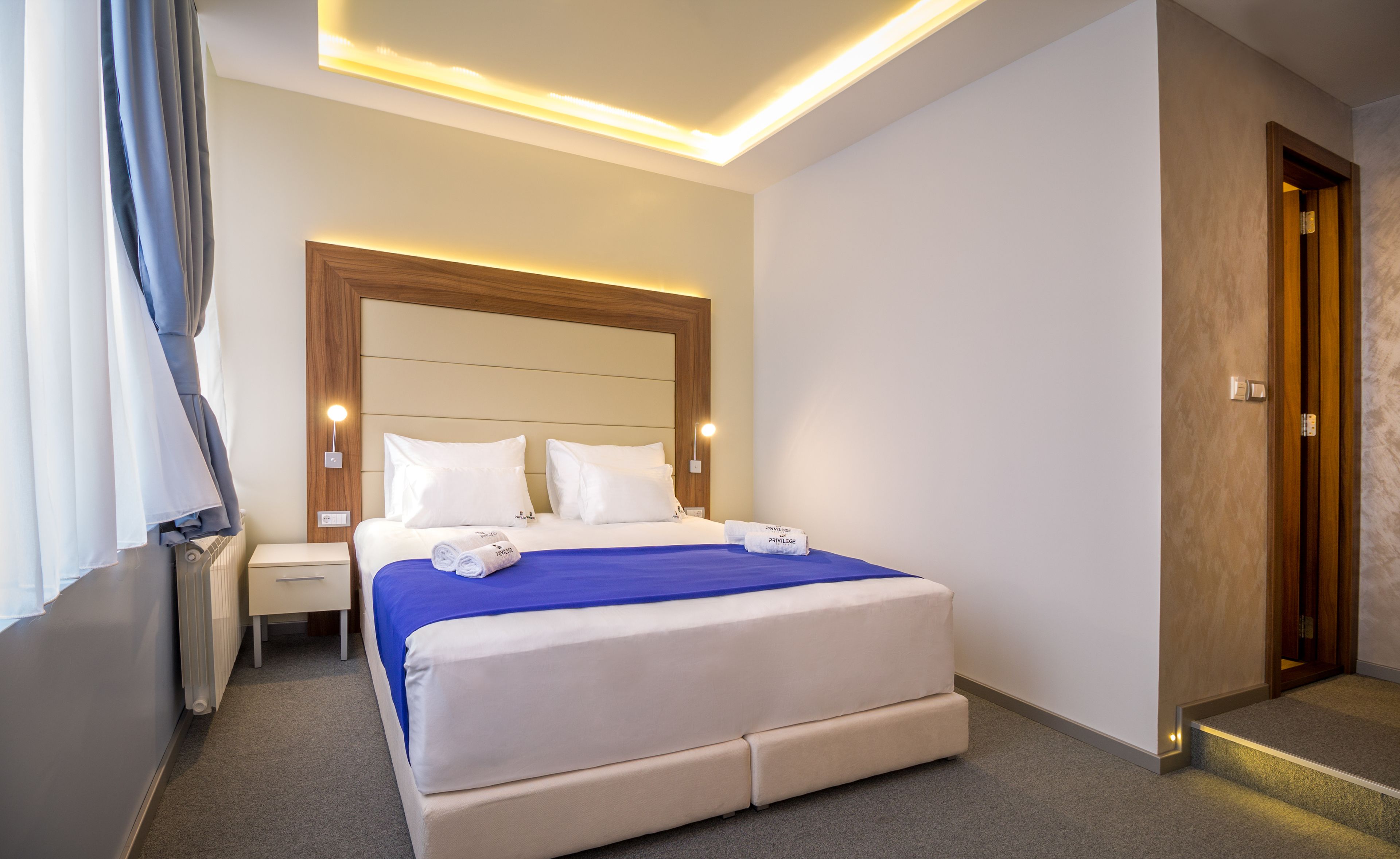A hotel room with a large bed, bedside tables, and a wooden headboard.