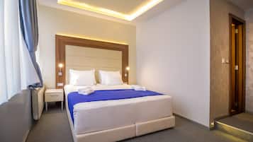 A hotel room with a large bed, bedside tables, and a wooden headboard.