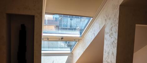 A room with a skylight, wooden flooring, and a visible window.