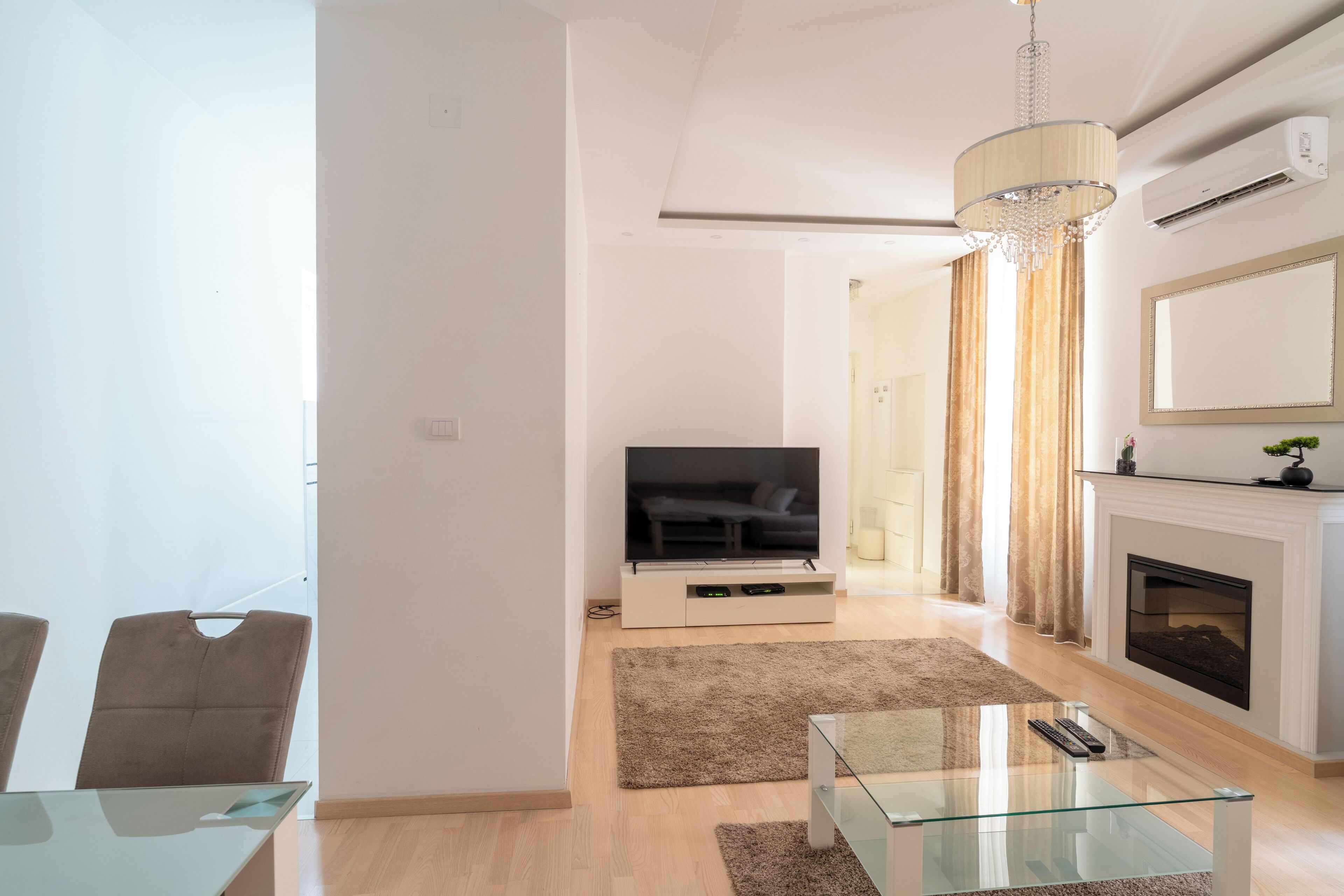 Een moderne woonkamer met een flatscreen televisie, een glazen salontafel en een open haard.