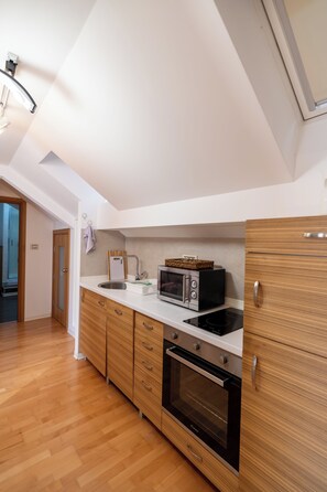Una cocina moderna con armarios de madera, horno empotrado, microondas y pileta.