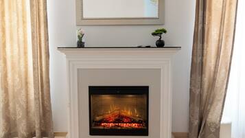 A room with a fireplace, a mounted mirror, and a ceiling-mounted air conditioning unit.
