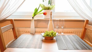 A dining table with a bowl of green grapes, a bottle of champagne, and two glasses. There is a vase with a red tulip and green leaves on the table. - Zajazd Agro nad Stawem (Zukowo)