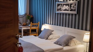 A hotel room with a bed, bedside table, chair, lamp, and a framed floral artwork on the wall. - Zajazd Agro nad Stawem (Zukowo)