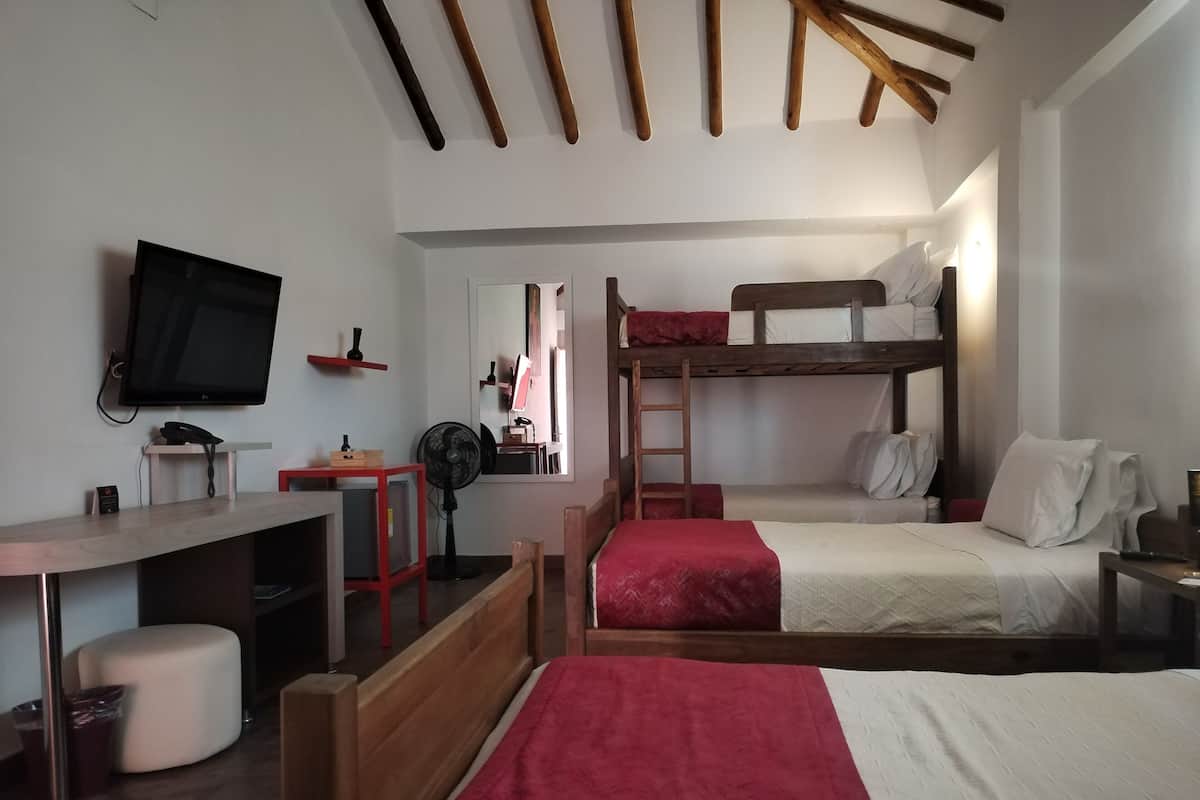 Una habitación con literas, un escritorio con computadora, un televisor y un espejo.