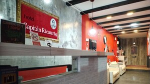 A hotel reception area with a red and white color scheme, a reception desk, and a seating area with white sofas. - Hotel Capitán Ricaurte (Villa de Leyva)