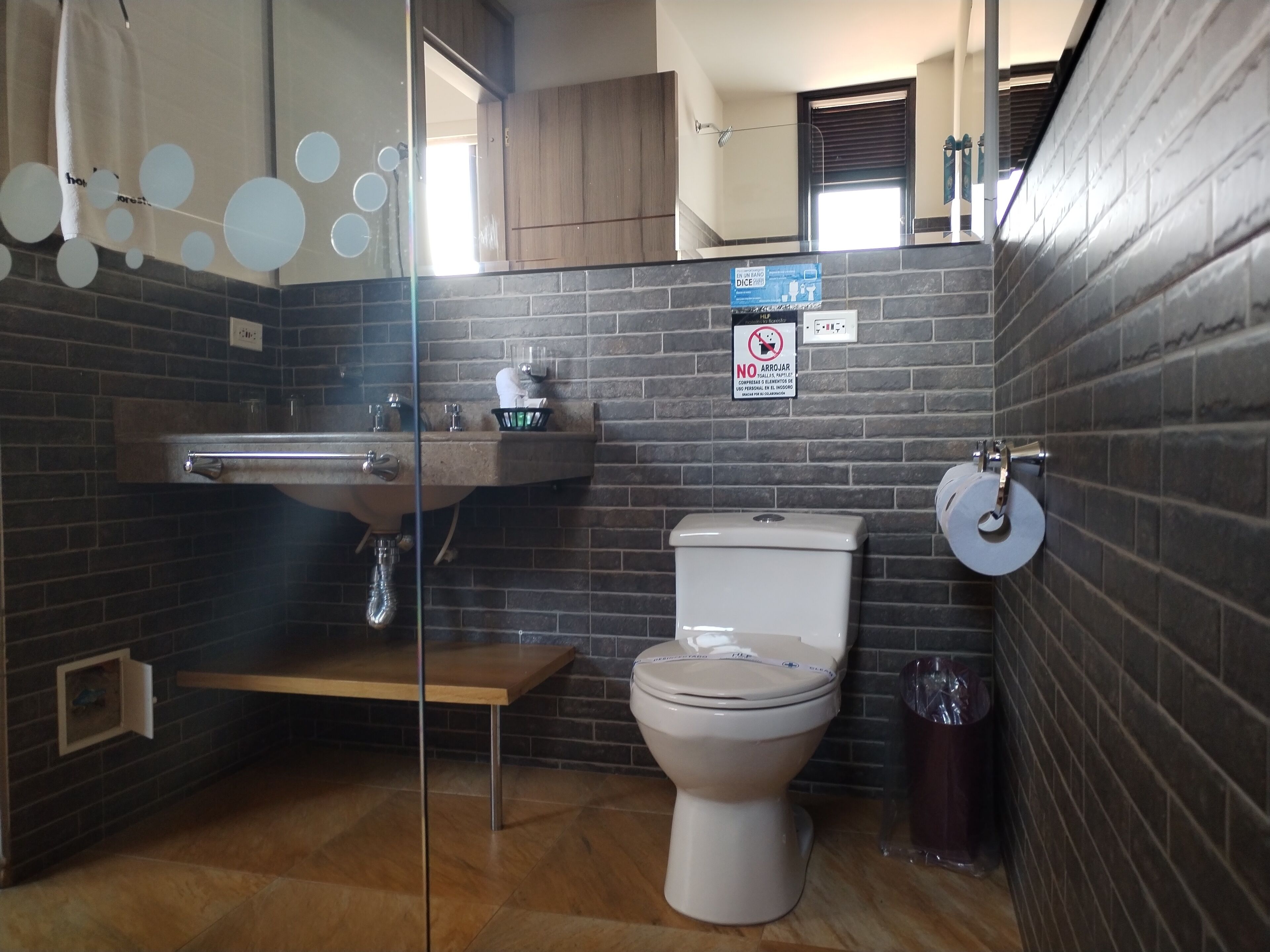A bathroom with a toilet, sink, and a glass partition.