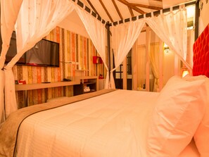 Un dormitorio con cama a dosel, televisor en la pared y una pared de acento roja.