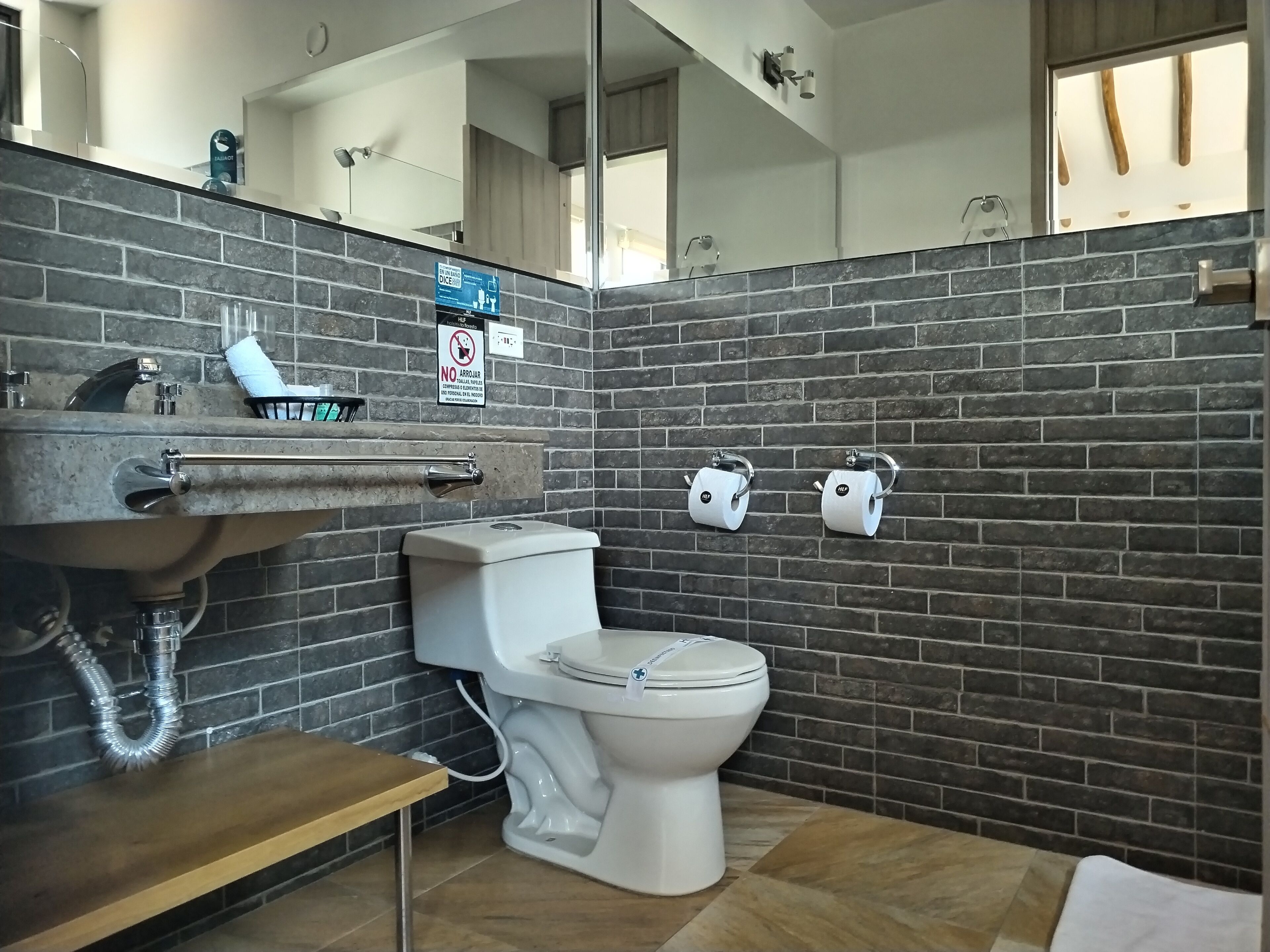 Un baño de diseño moderno, con lavamanos, inodoro y dos dispensadores de toallas de papel.
