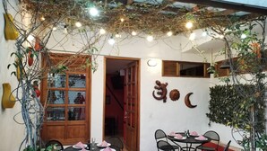 An outdoor dining area with tables and chairs, surrounded by plants and decorative lights. - Hotel Capitán Ricaurte (Villa de Leyva)