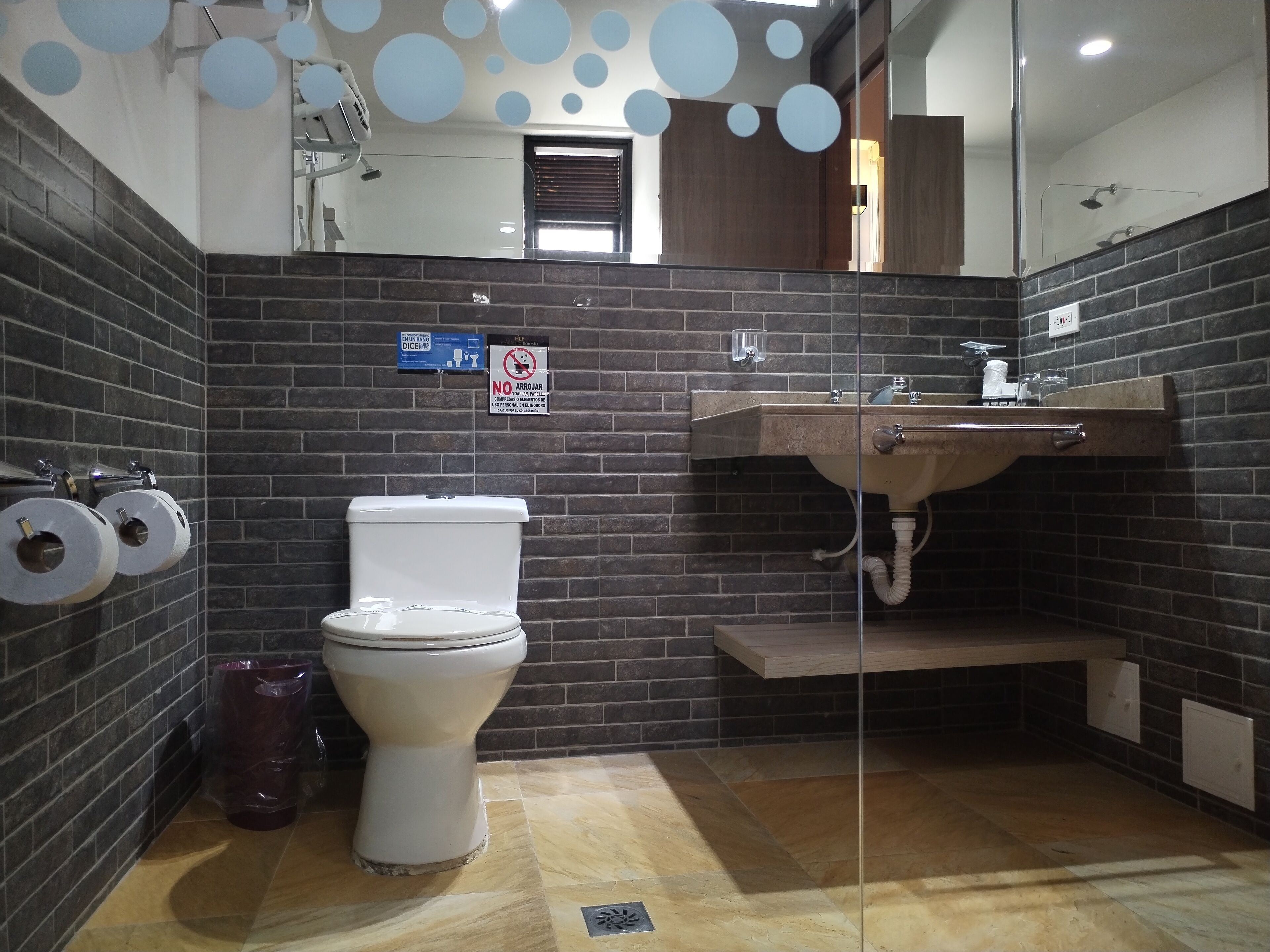 Ein modernes Badezimmer mit Toilette, Handtrockner und Waschbecken mit Spiegel darüber.