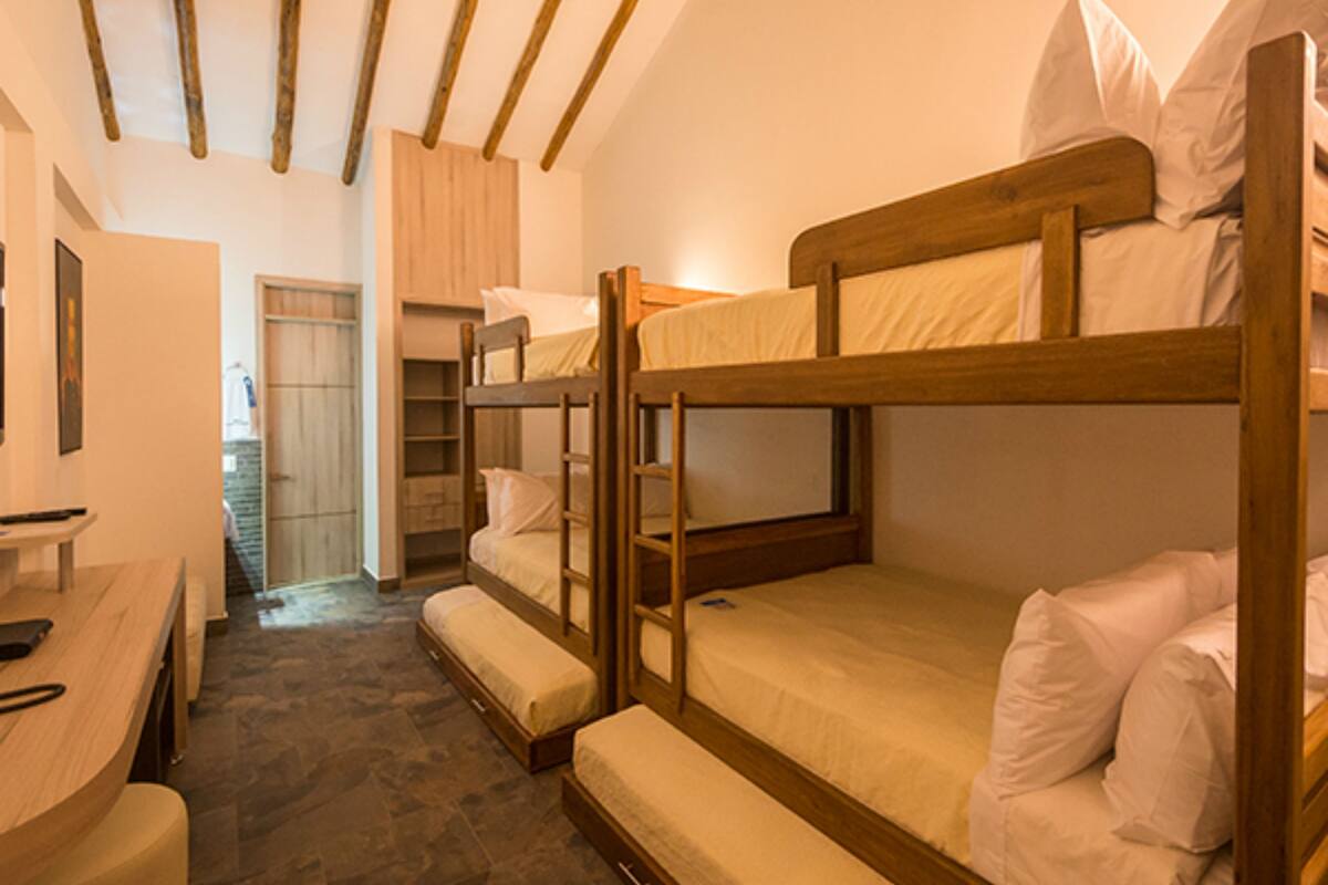 Habitación con literas, vigas de madera, escritorio y armario.