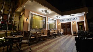 A hotel exterior with outdoor seating, large windows, and a sign reading "HOTEL Austria". - Hotel Austria (Tirana)