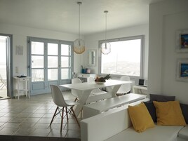 Una cocina moderna con armarios blancos, una mesa de comedor con sillas y un amplio ventanal con vistas a la ciudad.