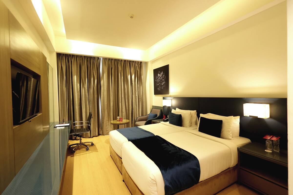 A hotel room with a large bed, bedside tables, a desk, and a chair.
