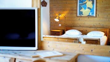 Una habitación de madera con dos camas, un escritorio y un televisor.