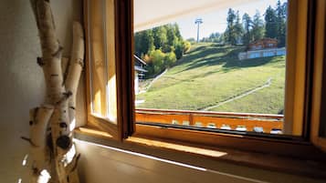 Ein Fenster mit Blick auf eine Wiese, einen Holzzaun und ein Gebäude in der Ferne.