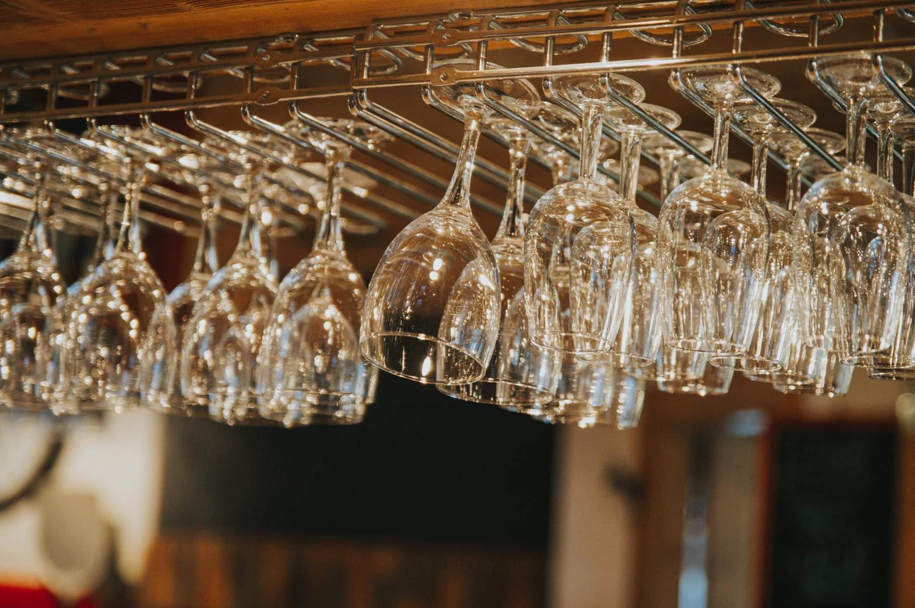 A rack of clear wine glasses hanging from a metal structure.