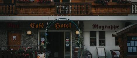 A building with a cafe, hotel, and bar signs.
