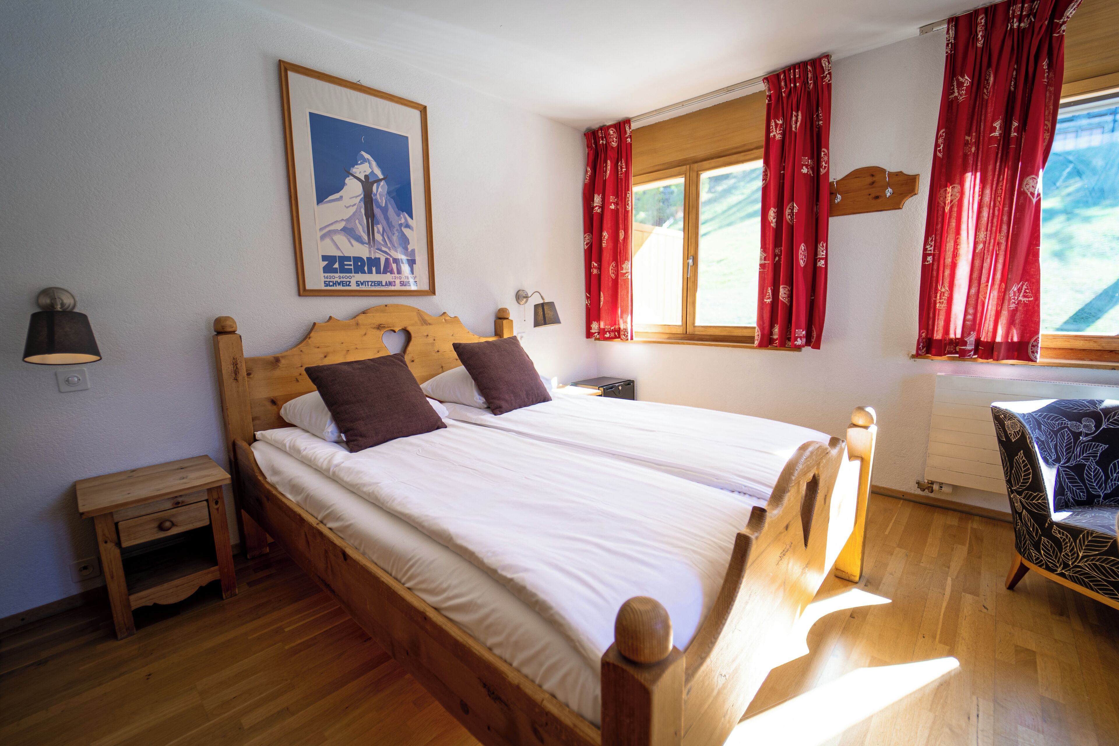 Una cama de madera con sábanas blancas, una mesita de noche, una lámpara y una silla con estampado floral.